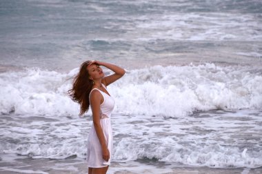 Kız okyanus arka plan üzerinde. Karayip denizin dalgaları beyaz elbiseli ince, güneşten kız yürüyor.