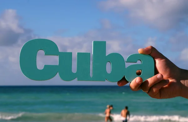 Cuba against the background of ocean. The advertising word Cuba on the background of the onane in the midst of the tourist season, which is held in the hand.