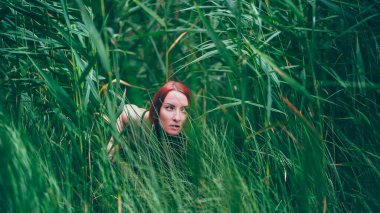 Tatilde. Gölde bikinili, şehvetli bir kız. Kızıl saçlı kadın bu şekilde rahatlarken eğleniyor. Yaz zamanı..