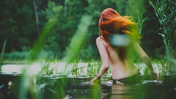 Nyaralni. Érzéki lány bikiniben a vízben a tavon. A vörös hajú nő élvezi a lazítást. Nyári időszak. — Stock Fotó