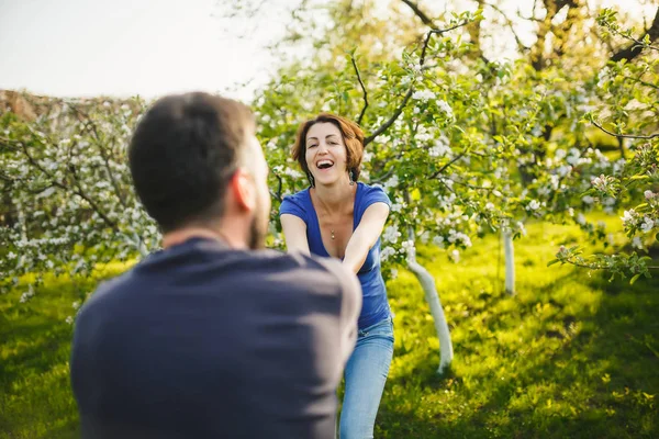 Hombre y mujer corriendo en floreciente jardín al atardecer — Foto de Stock