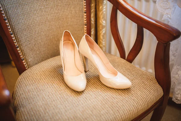 Brides white wedding shoes on vintage chair.