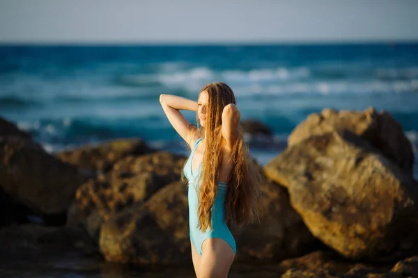 Сексуальная стройная модель, стоящая на камне на голубом морском фоне — стоковое фото