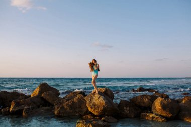 Güzel kız mavi deniz dalgaları zemin üzerine kayada duran