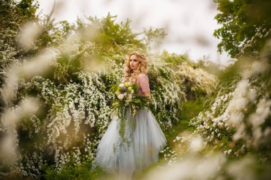 Beyaz çalılar zemin üzerine mavi elbiseli güzel genç gelin.