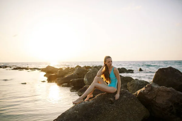Sexy schlankes Modell sitzt auf Felsen auf blauem Meeresgrund — Stockfoto
