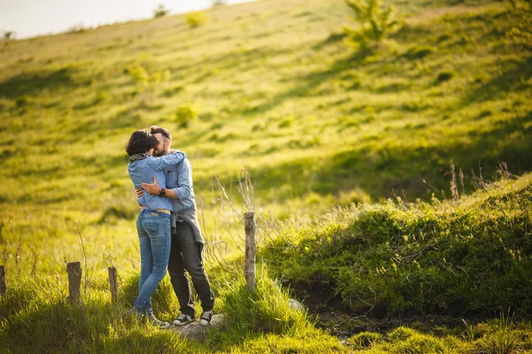 Pareja besándose en campo prado en la primavera al atardecer — Foto de Stock
