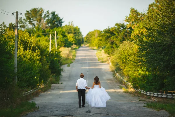 Joven pareja recién casada caminando por el camino del campo —  Fotos de Stock