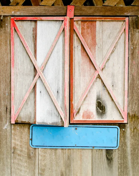 Vecchia finestra di legno invecchiato rosso incorniciato con vuoto segno etichetta blu — Foto Stock