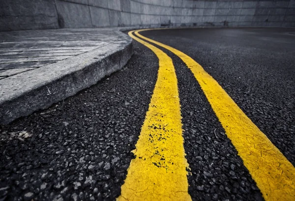 Detalle de doble línea amarilla curvada sobre asfalto negro —  Fotos de Stock