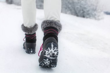 Detail of woman lifting her black and gray snow boot clipart