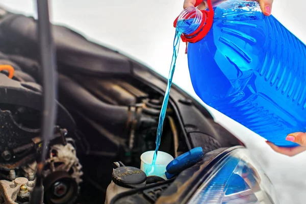Vrouw gieten antivries auto scherm vloeistof in vuile auto wassen — Stockfoto
