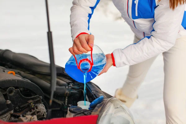 Woman in ski jacket pouring antifreeze car screen wash liquid in — Stock Photo, Image
