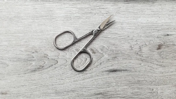 Manicure cuticle scissors on laminate flooring that looks like w — Stock Photo, Image