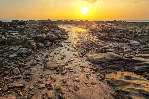 Rocks and beach uncovered in low tide with boats on dry land in — Stock Photo, Image