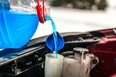 Detail on pouring antifreeze liquid screen wash into dirty car  clipart