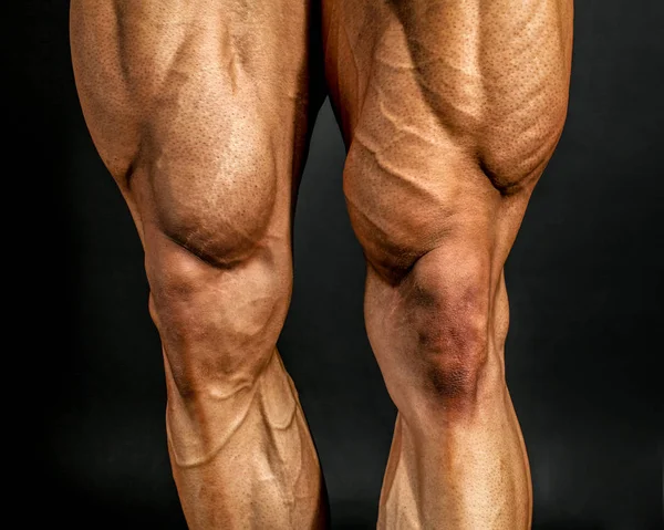 Detail of male bodybuilder front leg muscles on black background — Stock Image Detail of male bodybuilder front leg muscles on black background Stock Photo