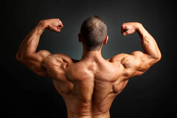 Young bodybuilder man flexing back double bicpes pose, showing h — Stock Photo, Image
