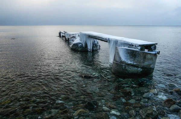 Molo di legno in mare coperto di ghiaccio e neve con ghiaccioli . — Foto Stock
