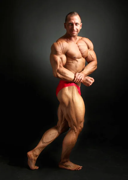 Νεαρά αρσενικά bodybuilder ποζάρει, δείχνει τους μυς του μπροστά στο στήθος, — Φωτογραφία Αρχείου