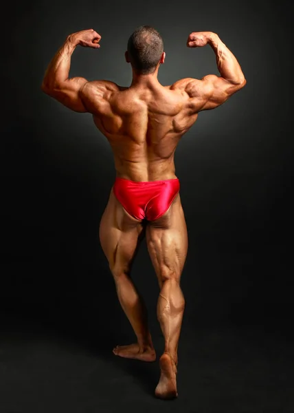 Giovane bodybuilder uomo flessione posteriore doppia posa bicpes, mostrando h — Foto Stock