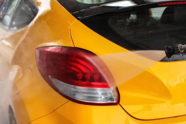 Detalle de la luz trasera del coche amarillo que se lava en el coche lavado . — Foto de Stock