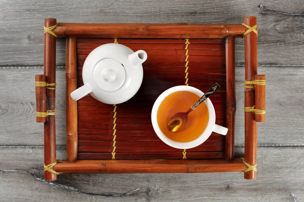 Table top view on bamboo wood tray with small ceramic teapot and — Stock Photo, Image