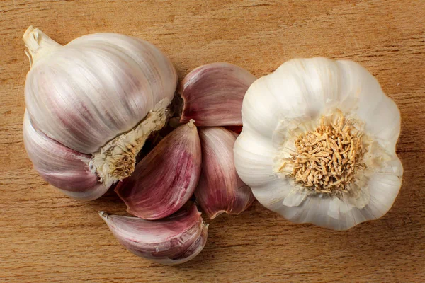 Top view on garlic bulb and cloves placed on old working board w — Stock Photo, Image