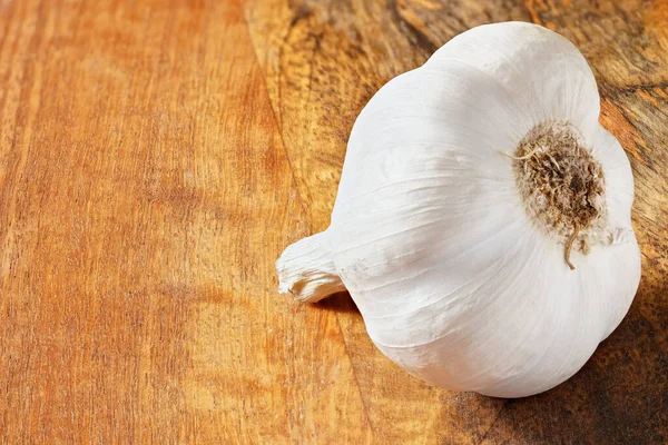 Single garlic bulb on wooden kitchen board, space for text left side, closeup macro — Stock Photo, Image