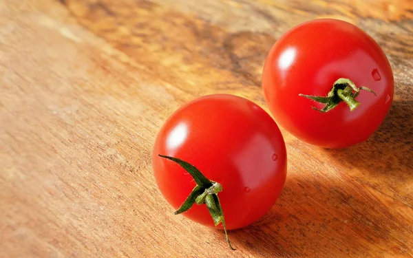 Dvě jasně červená cherry rajčata na dřevěné desce, prostor pro text vlevo. Podrobné uzavření makra — Stock fotografie
