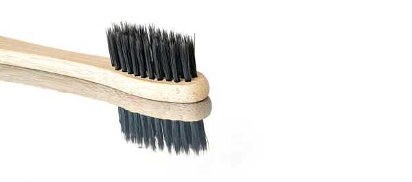 Houten bamboe tandenborstel met zwarte borstels, close-up detail geïsoleerd op glanzende witte tafel reflectie zichtbaar, ruimte voor tekst rechterkant — Stockfoto