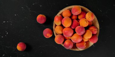 Kayısılar küçük kasede, bazıları tahta gibi siyah mermerler üzerine dağılmış, başınızın üstünde de fotoğraf var.