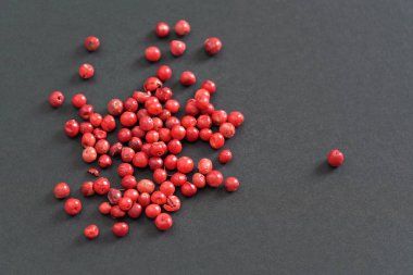 Tüm pembe kırmızı biberler siyah gri kağıt üzerinde, yukarıdan görünüyor.