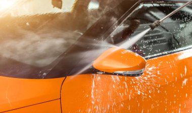 Bencilce yıkanmış turuncu araba. Araba yıkama, beyaz şampuan ve köpük. 