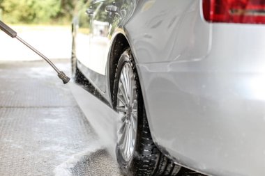 Gümüş arabanın yan ve arka tekerlekleri oto yıkamada yıkanmış.,