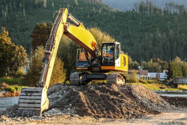 Sarı kazıcı (kazıcı makinesi) taşları kazıyor, nehirde, önde