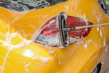 Sarı araba arka lambası oto yıkamada yıkanmış. Fırça Temizleyici