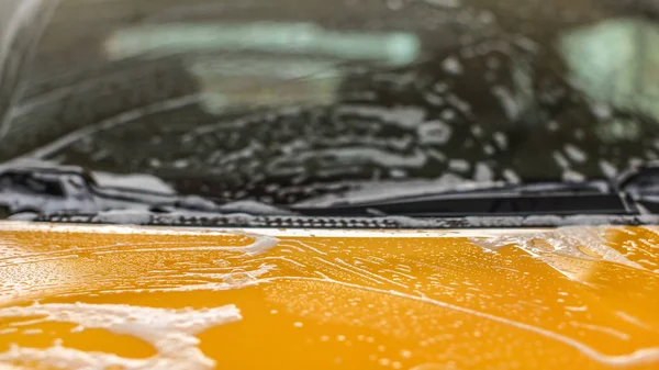 Closeup detail - front hood of yellow car covered with white sha — Stock Photo, Image