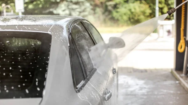 Önkiszolgáló autómosóban mosott ezüst autó oldala. Vízsugár — Stock Fotó