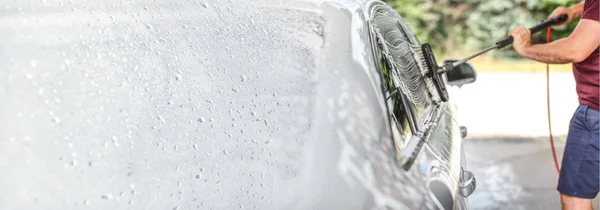 Man wast zijn auto bij zelfbediening carwash, borstel schoonmaak glas — Stockfoto