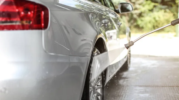 Rear wheel of silver car washed in self serve carwash, water spr — Stock Photo, Image