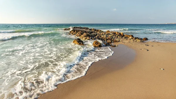 Après-midi soleil brille sur la plage sauvage, quelques petites vagues frappant allumé — Photo