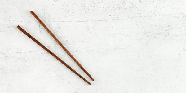 Flat lay photo - pair of dark wood chopsticks on white board. Wi — Stockfoto