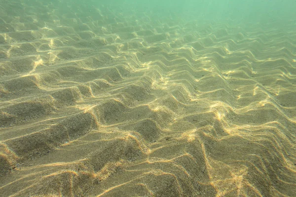 Underwater photo, sun shining on sea floor in shallow water, san — Stockfoto