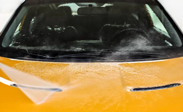 Water jet spraying on front of yellow car washed in self serve c — Stock Photo, Image