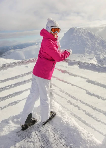 ピンクのスキージャケット、パンツブーツ、帽子と手袋、革の若い女性 — ストック写真