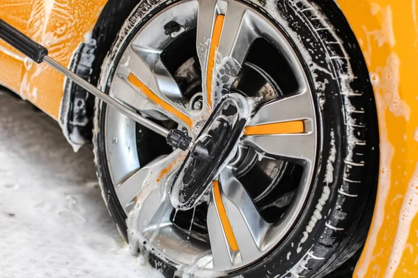 Roda de carro amarelo lavado em auto-serviço de lavagem de carros, limpeza escova — Fotografia de Stock