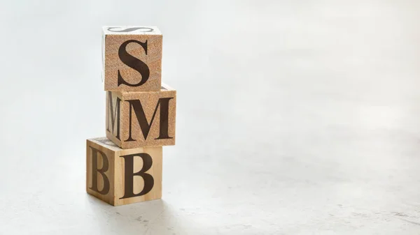 Куча с тремя деревянными кубиками - буквы SMB, означающие от малого до меди — стоковое фото