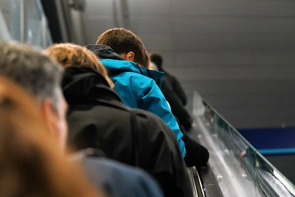 Personas anónimas subiendo las escaleras mecánicas, vista desde atrás, detalle en sus cabezas - concepto de transporte —  Fotos de Stock