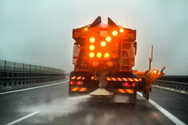 Highway maintenance gritter truck spreading de icing salt on roa